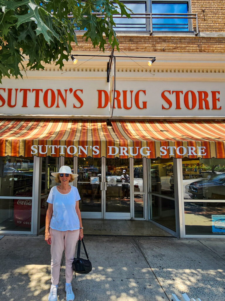 woman standing outside sutton's drug store