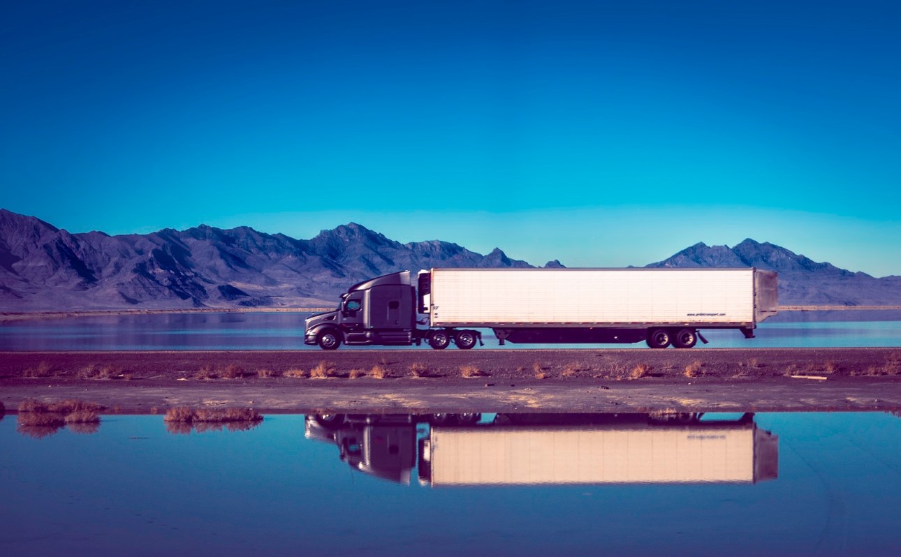 The semi truck confronts the dangers of the winding, high voltage western road, surrounded by raw power and natural beauty