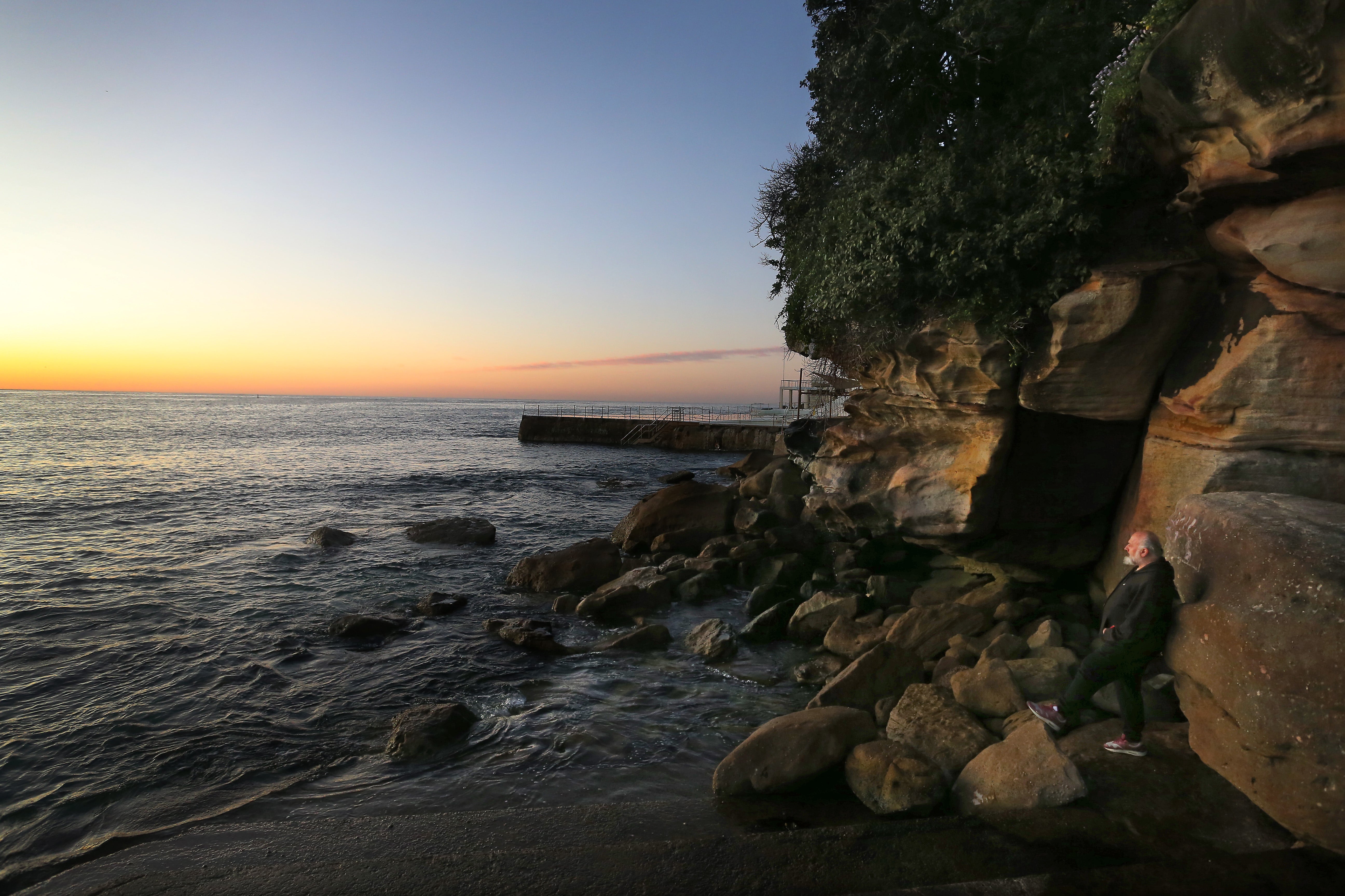 A man looks out across Bondi Beach at sunrise in Sydney, Australia