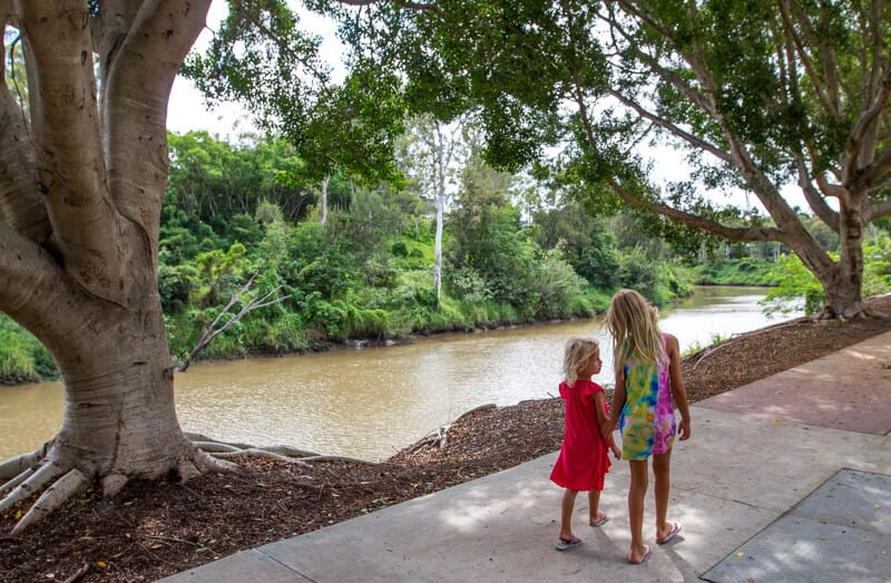 girls walking on a path next to a river