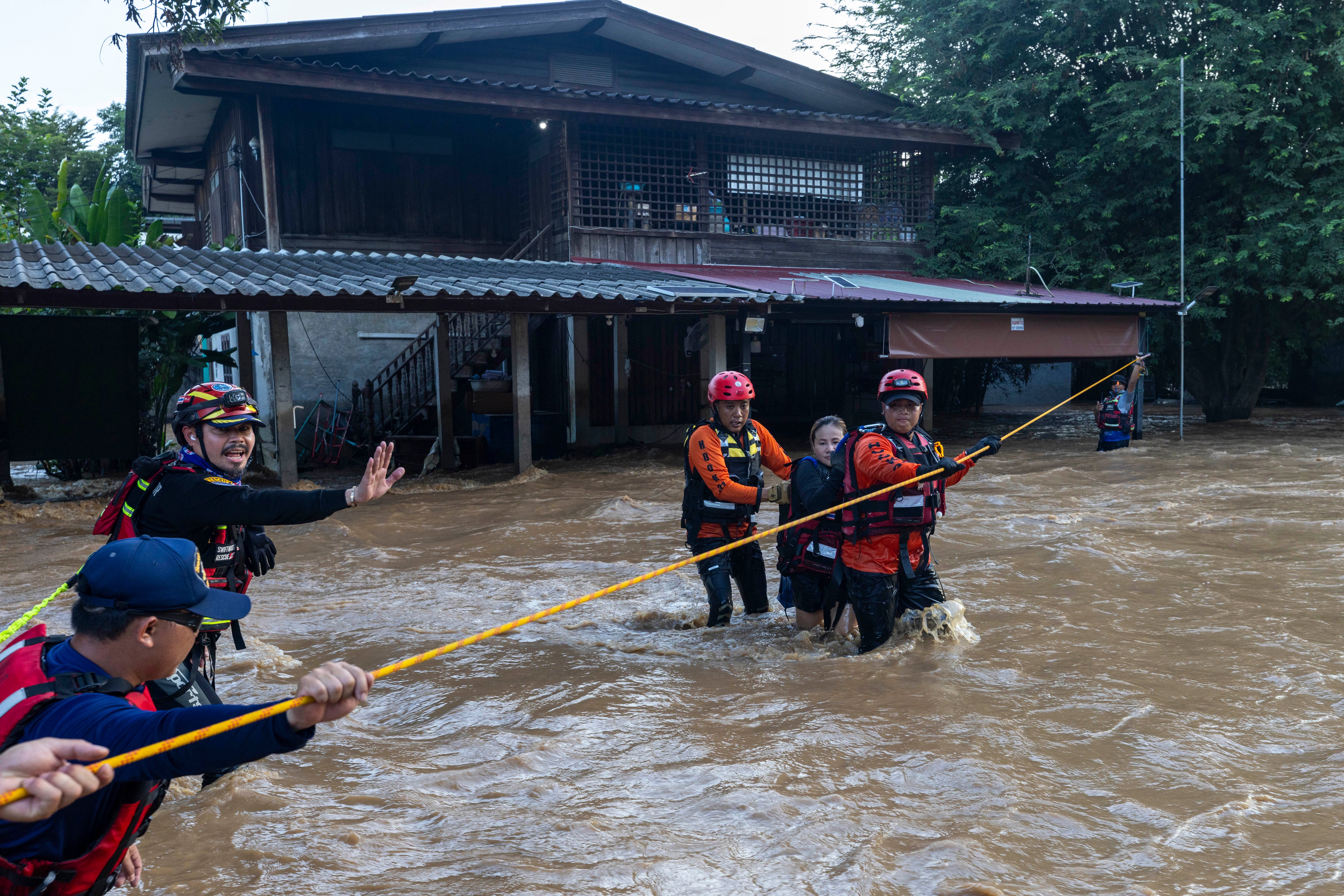 Thai rescuers help a woman from a flood-hit area in Chiang Mai Province, Thailand