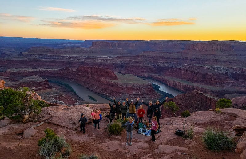 people posing with the Dead Horse Point State Park sunset behind them