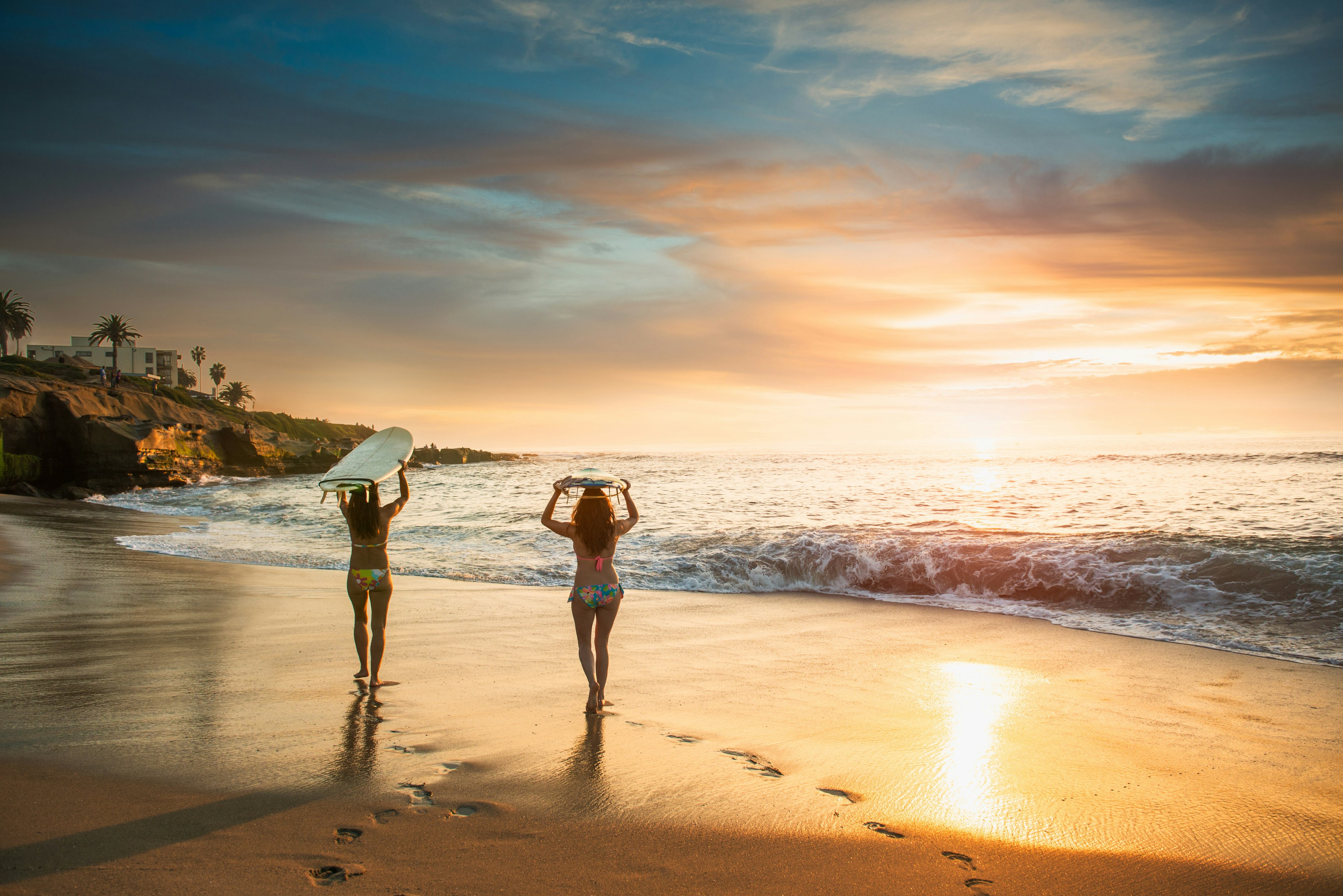 Surfers carrying surf board, walking along beach