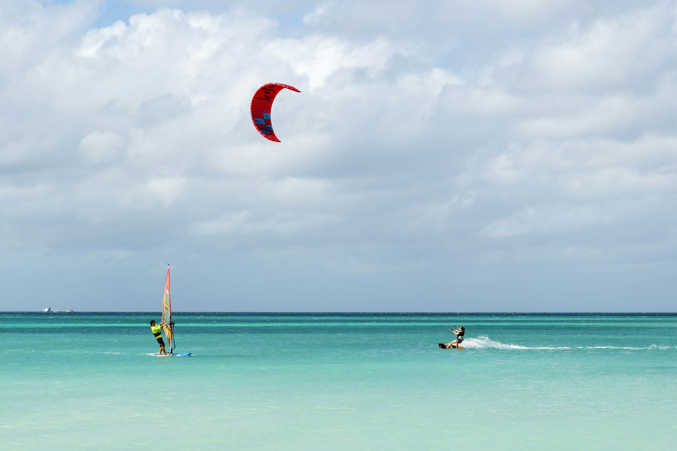 A windsurfer and a kitesurfer enjoy water sports