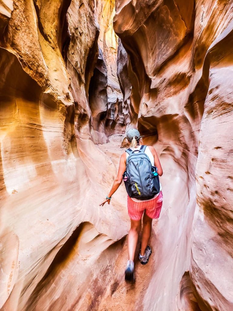 woman walking through peek a boo slot canyon