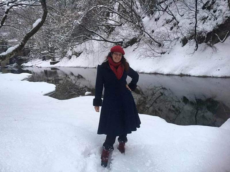 girl standing in snow beside creek