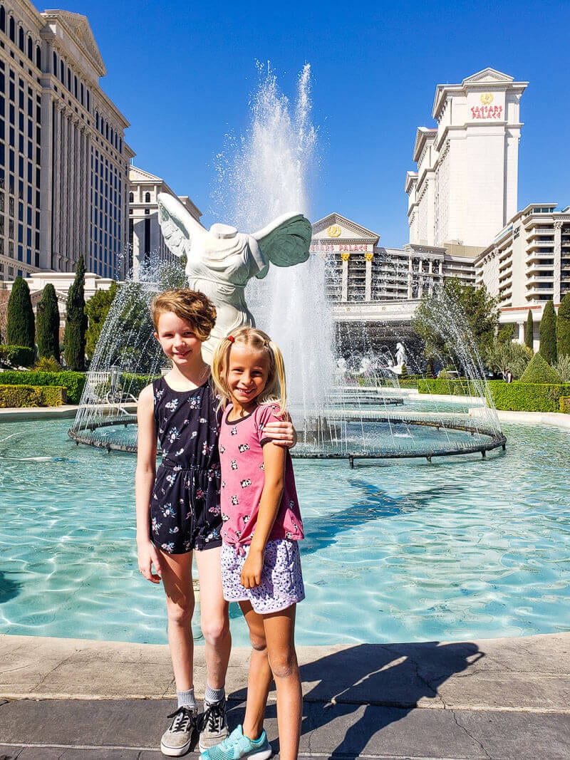 two girls hugging in front of fountain