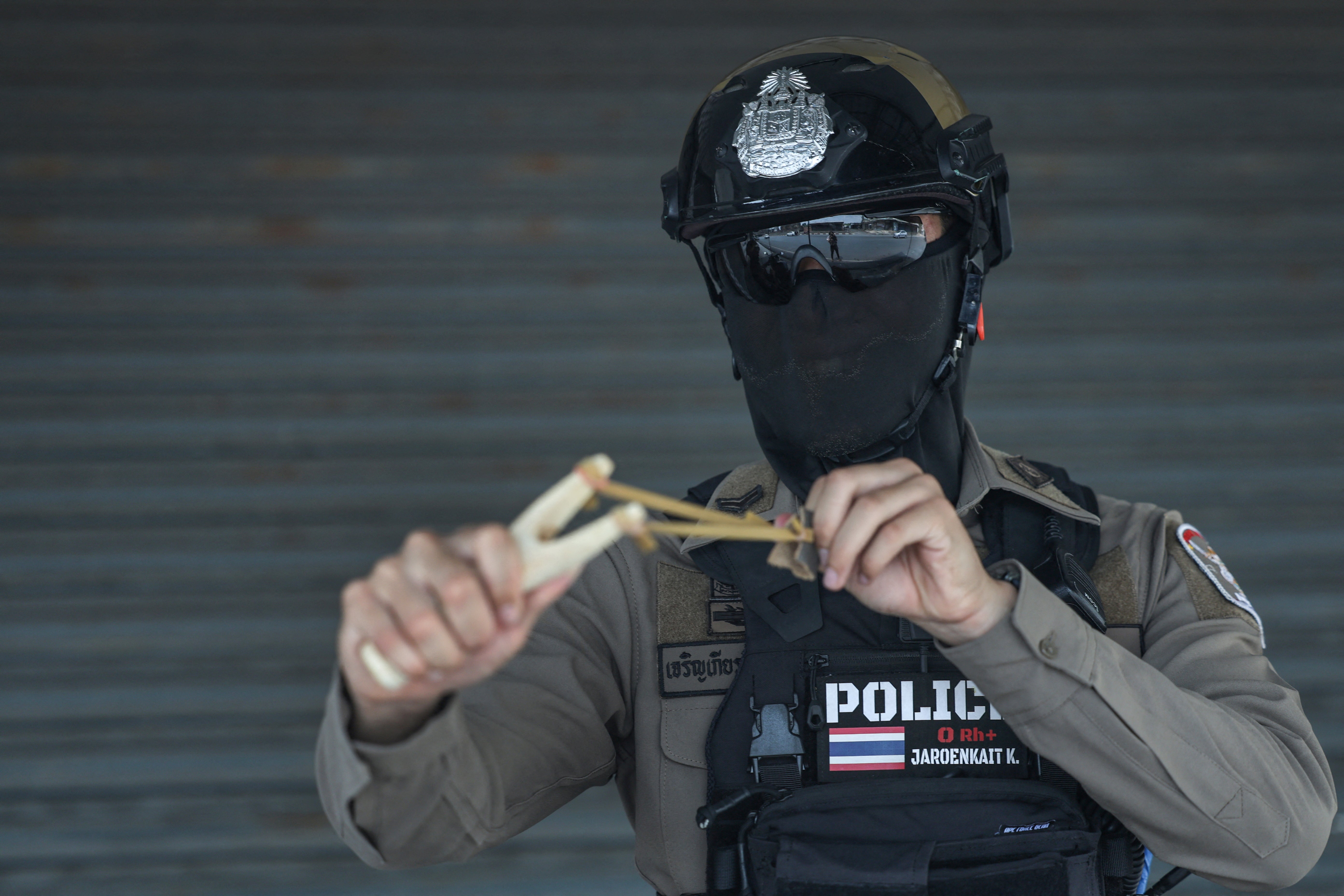 A policeman poses for a photo with a slingshot used to scare long-tailed macaques away, as officials started capturing monkeys in Lopburi, Thailand