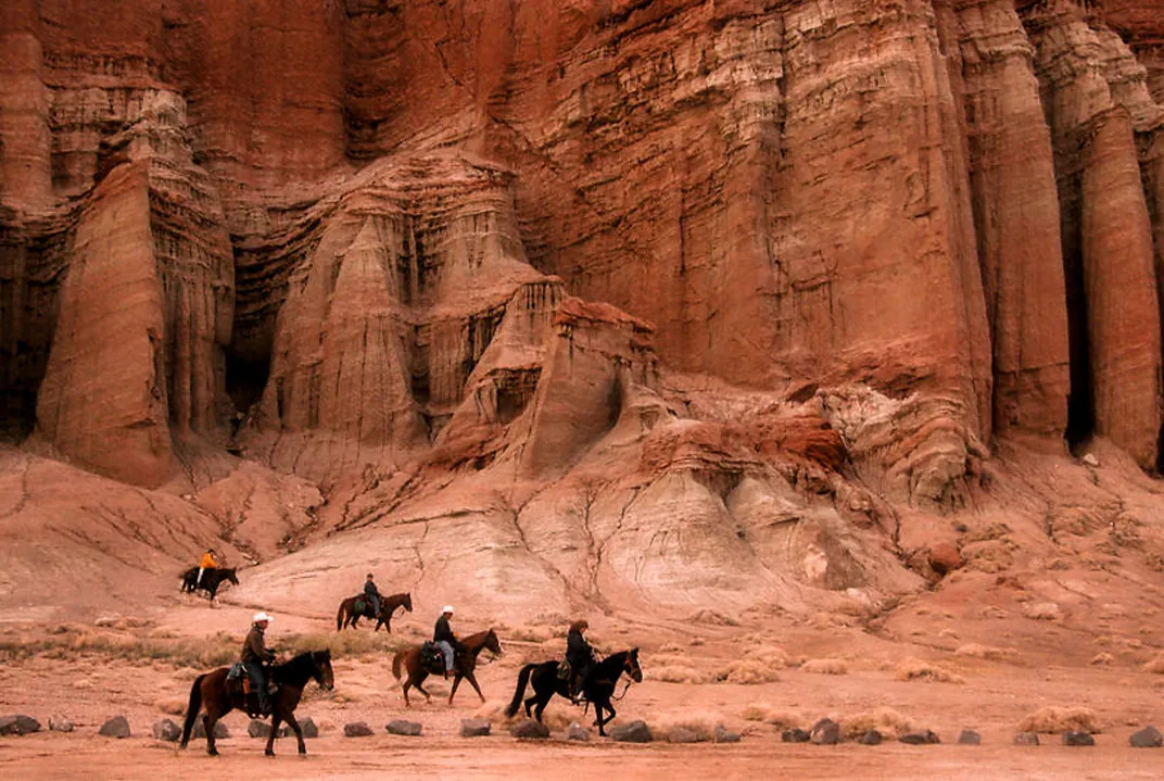 Five people on horseback ride in the desert