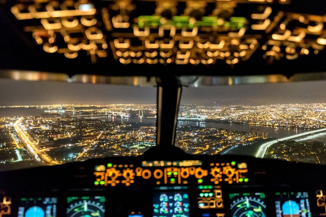 4 - The illuminated cockpit of an airplane complements the bright lights of the city of Guayaquil below.