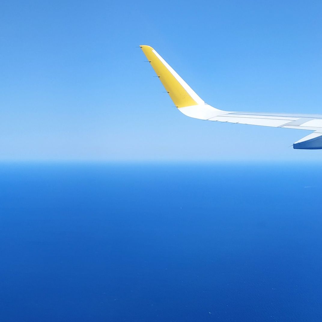 8 - A passenger snapped this photo of an airplane wing against the blue backdrop of the sky and sea over Barcelona.