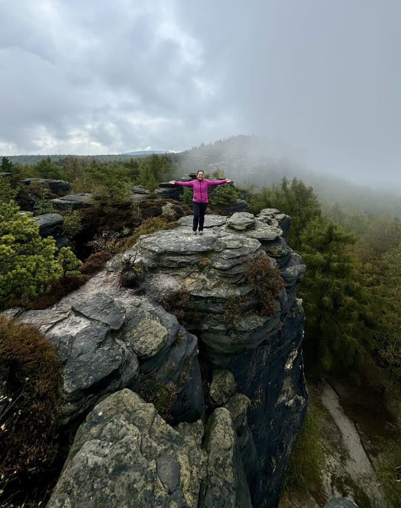 Kate standing on a tall rock formation, foggy rocks behind her.