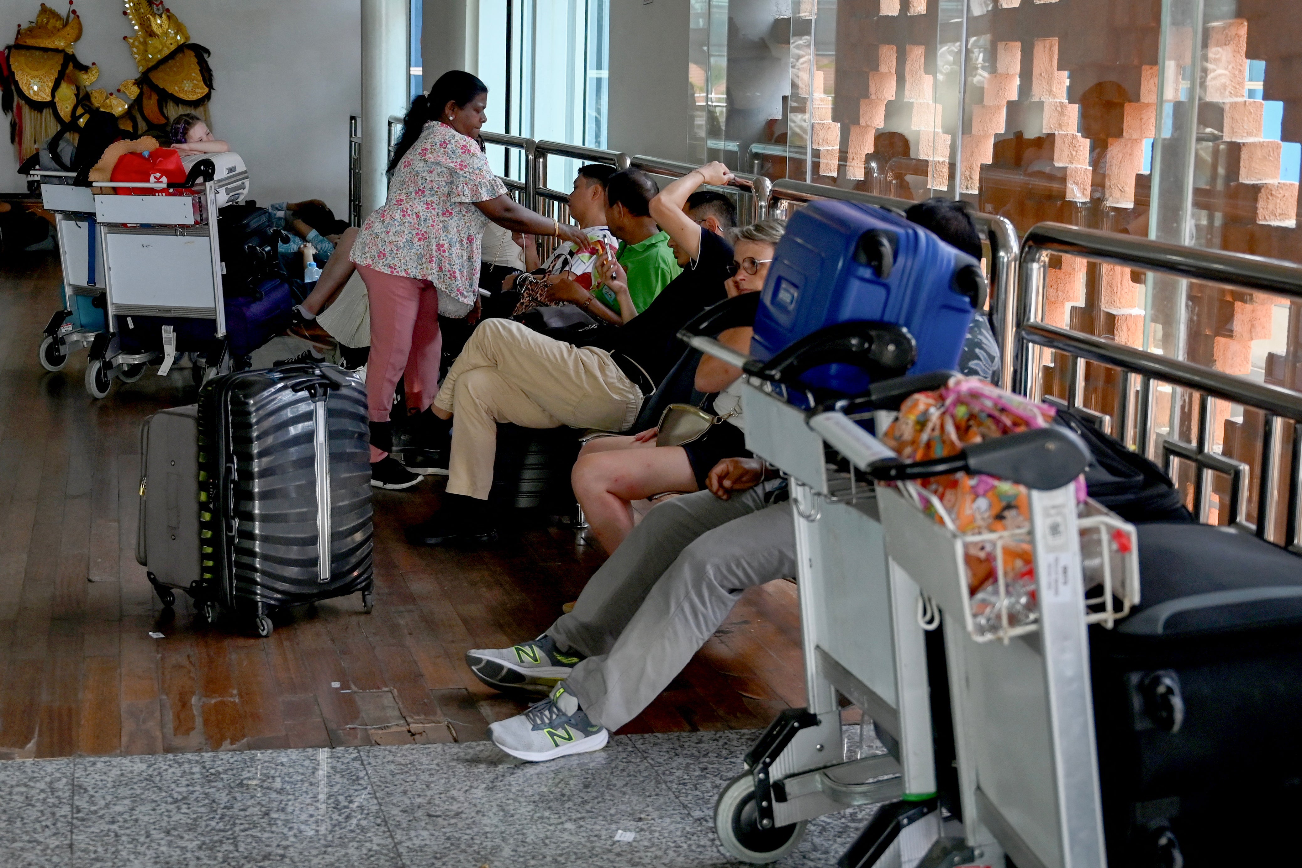 Passengers wait at the Ngurah Rai International Airport in Bali after flight cancelations