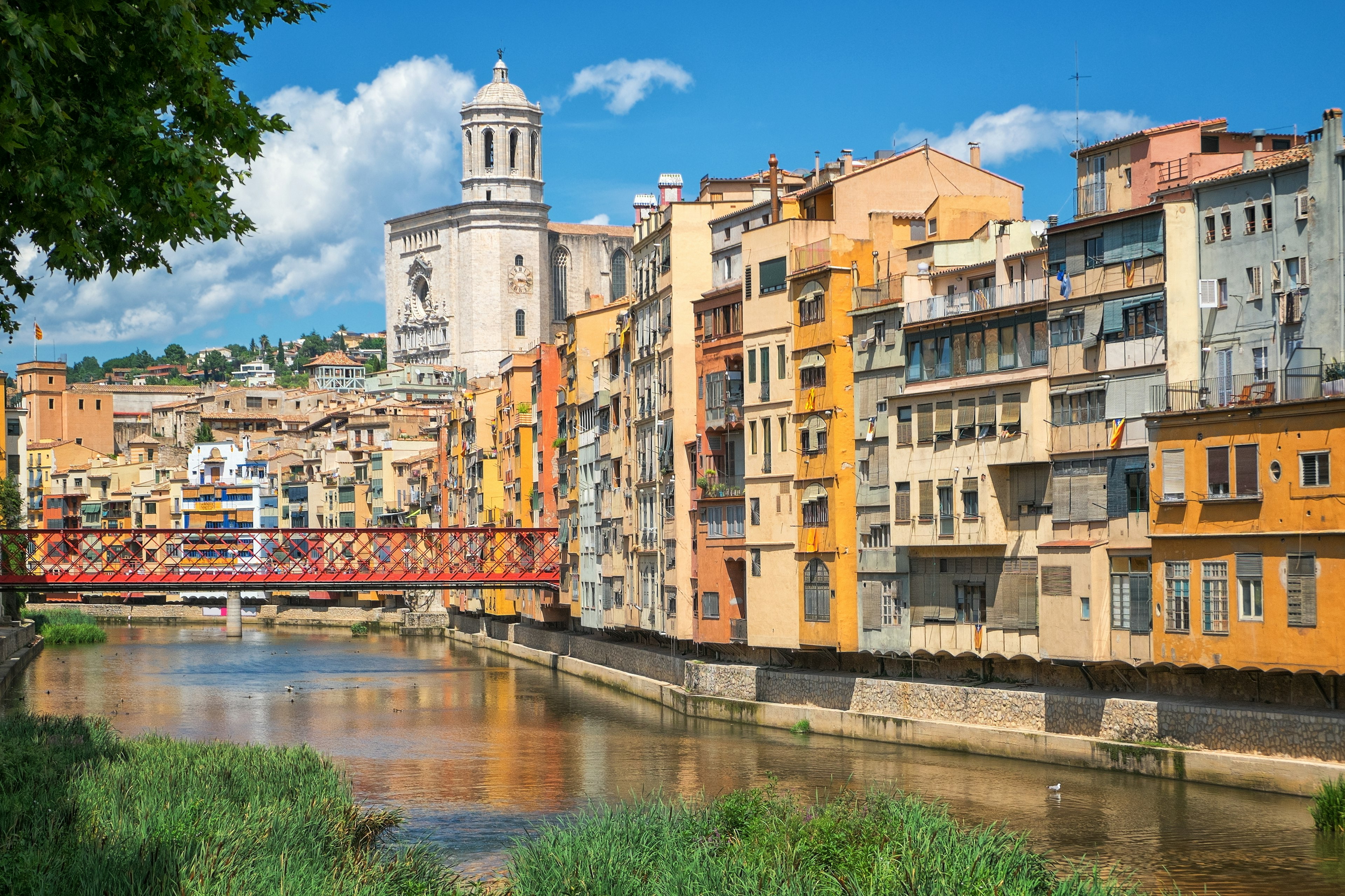 A city with buildings in pastel-hues of orange and yellow lining a riverside