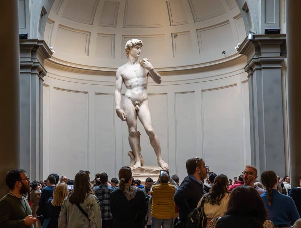 The statue of David, surrounded by people taking pictures of it.