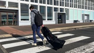 A golfer walking into an airport with the Titleist Players Travel Cover