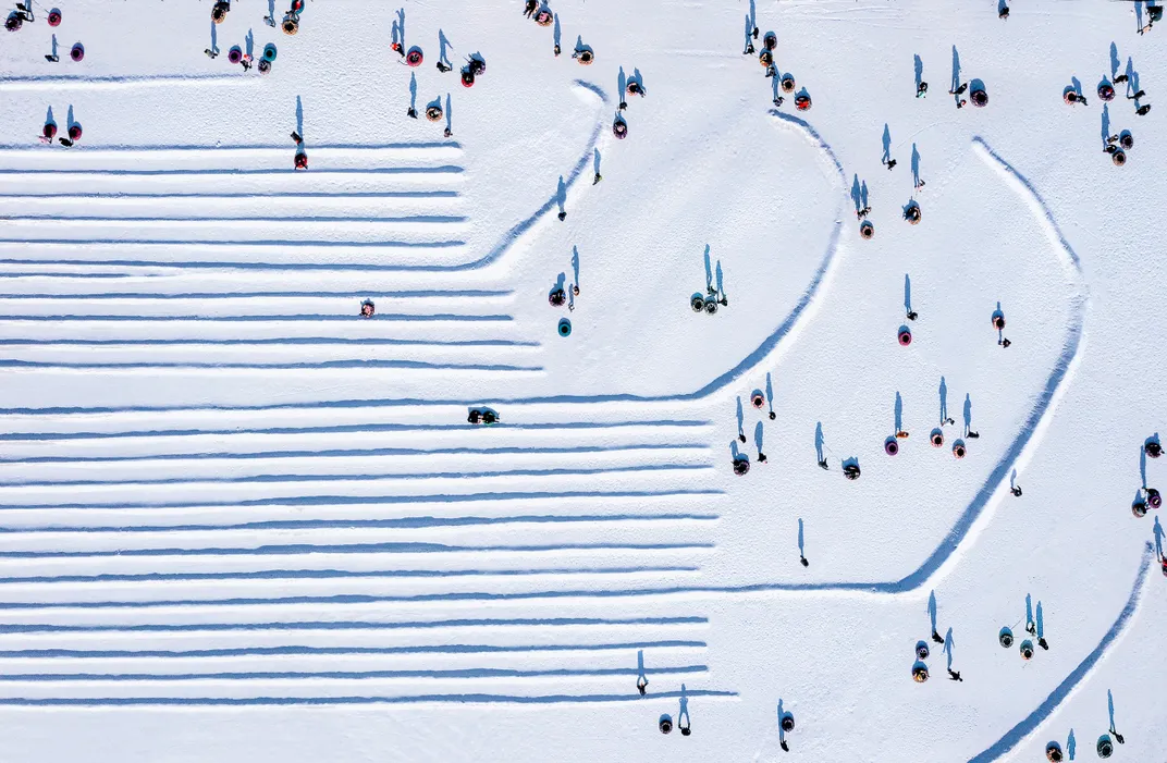 6 - People’s shadows dot the landscape as snow tubers wait for their chance for a thrilling and frigid ride.