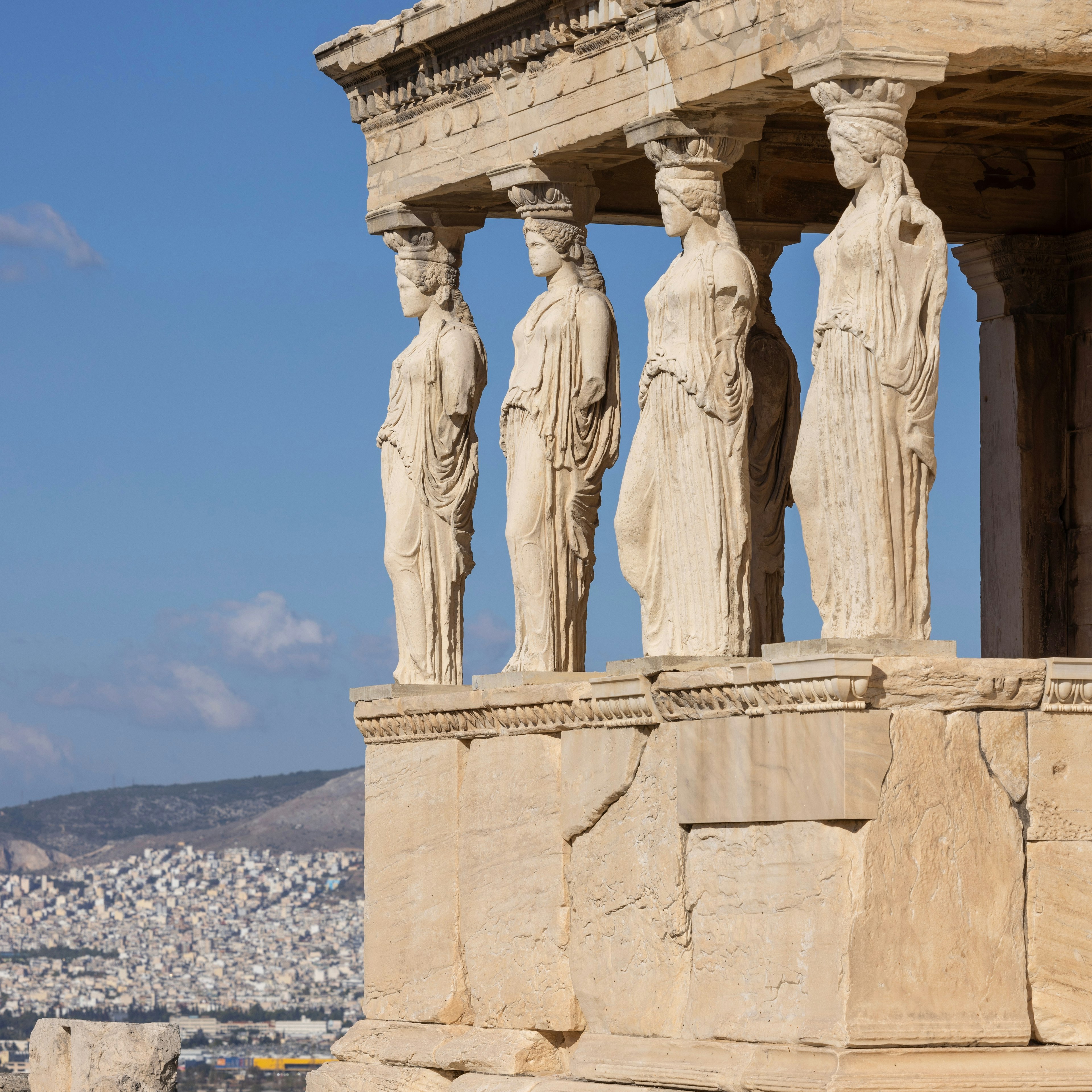 Four columns sculpted to look like women hold up an ancient ruin in Greece.