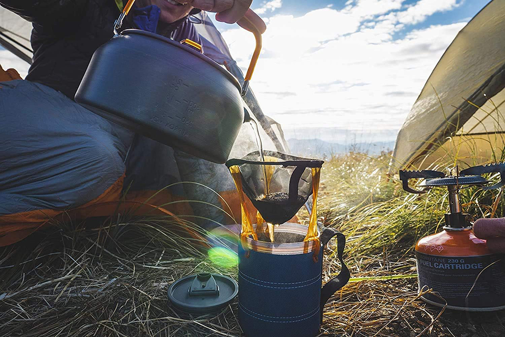 A camper pours water into the coffee maker