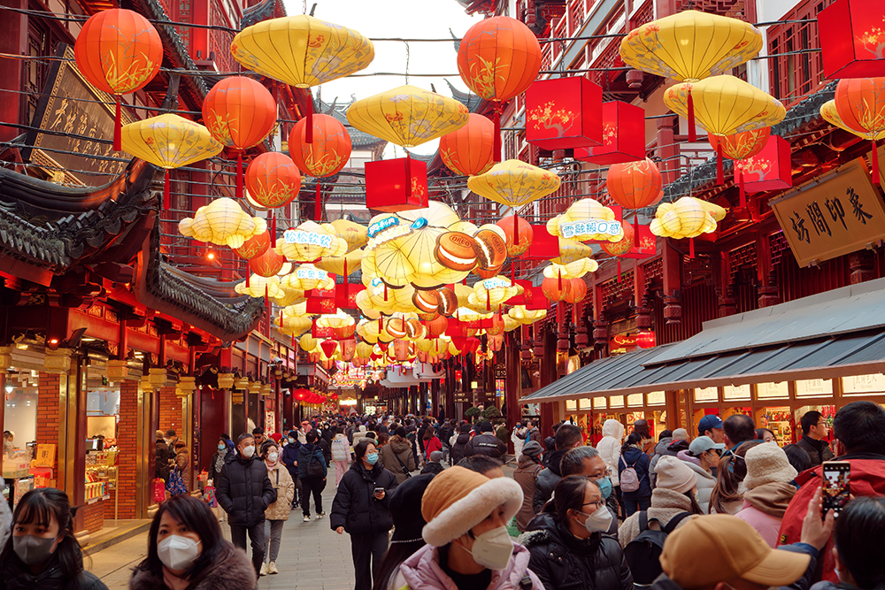 People walking under red and yello lanterns in Shanghai