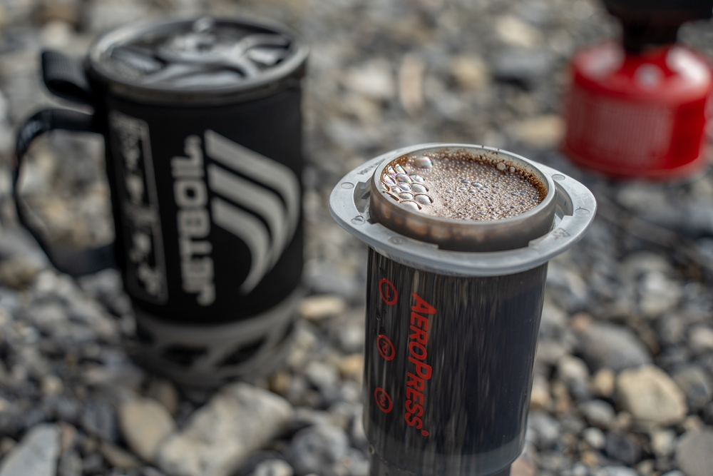 An Aeropress coffee maker filled with coffee on the ground