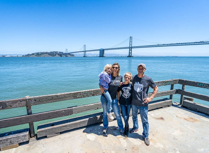 family posing in front of bay bridge