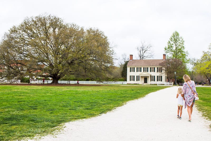 mother and child walking on a dirt path towards building at Colonial Williamsburg