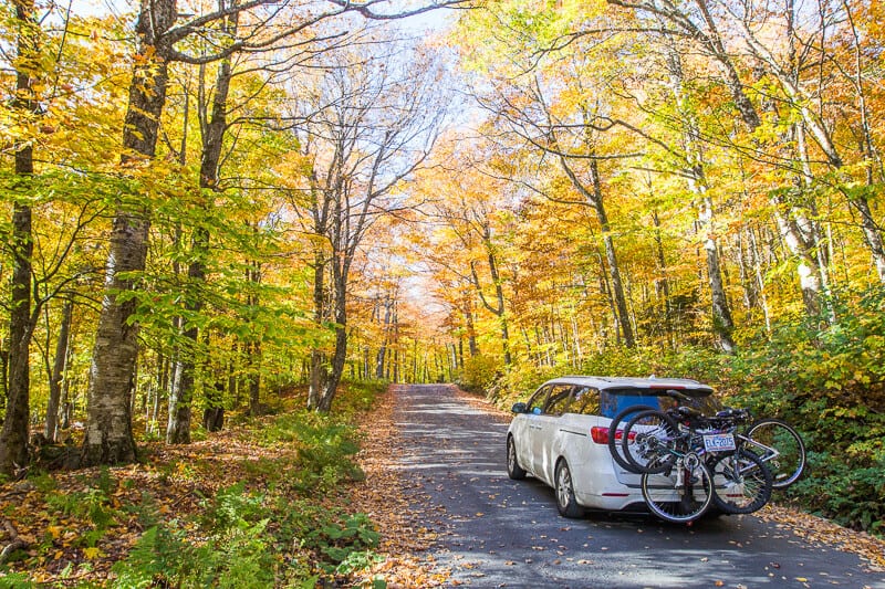 car on road lined with fall foliage t Mount Mansfield toll road Stowe Vermont