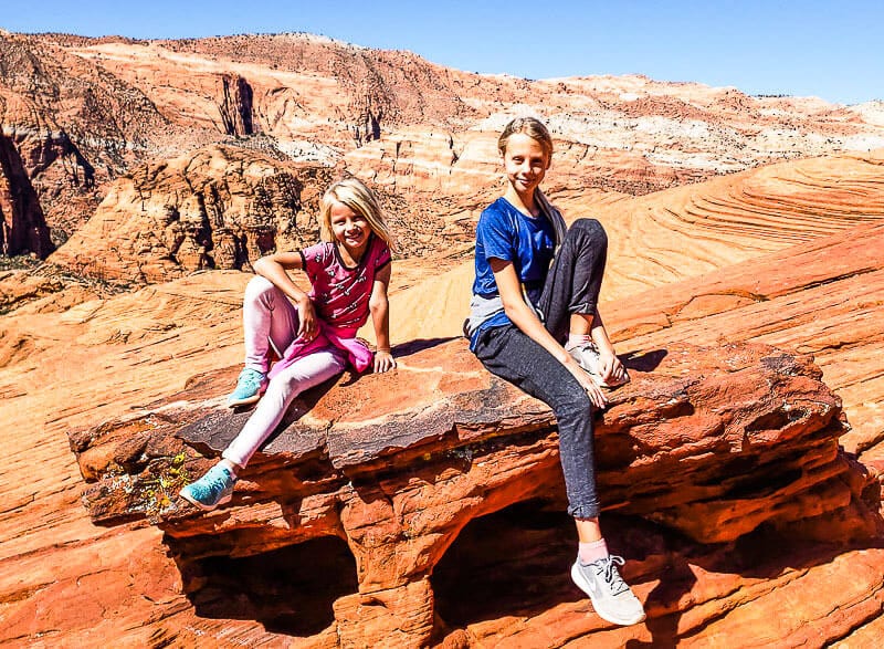 girls sitting on a red rock