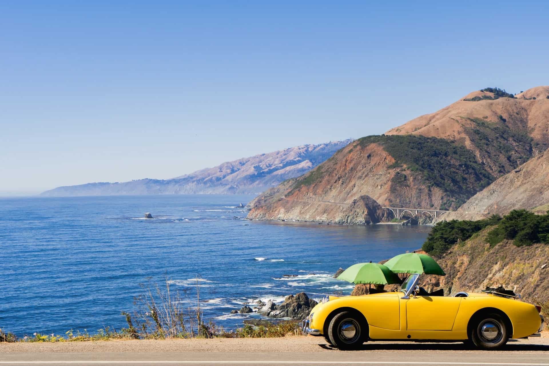 Yellow convertible parked on Route 1 in Big Sur, California (photo by Abhi Verma, Unsplash).
