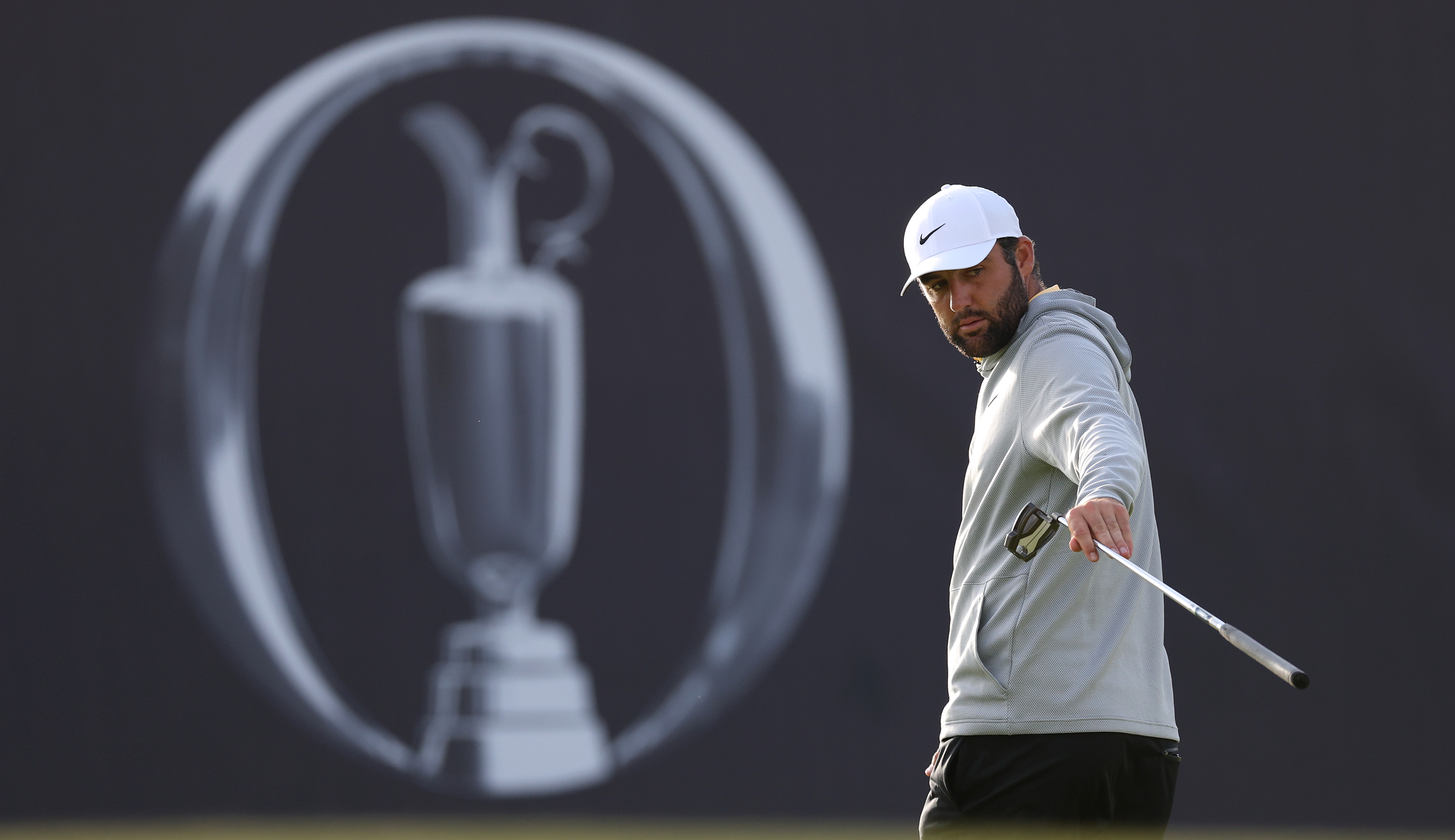 Scottie Scheffler points at the hole in front of an Open Championship logo