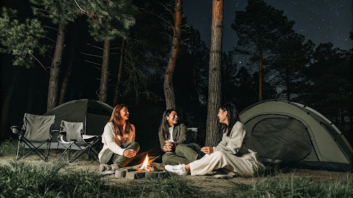 women camping at night with tents and a campfire outdoors