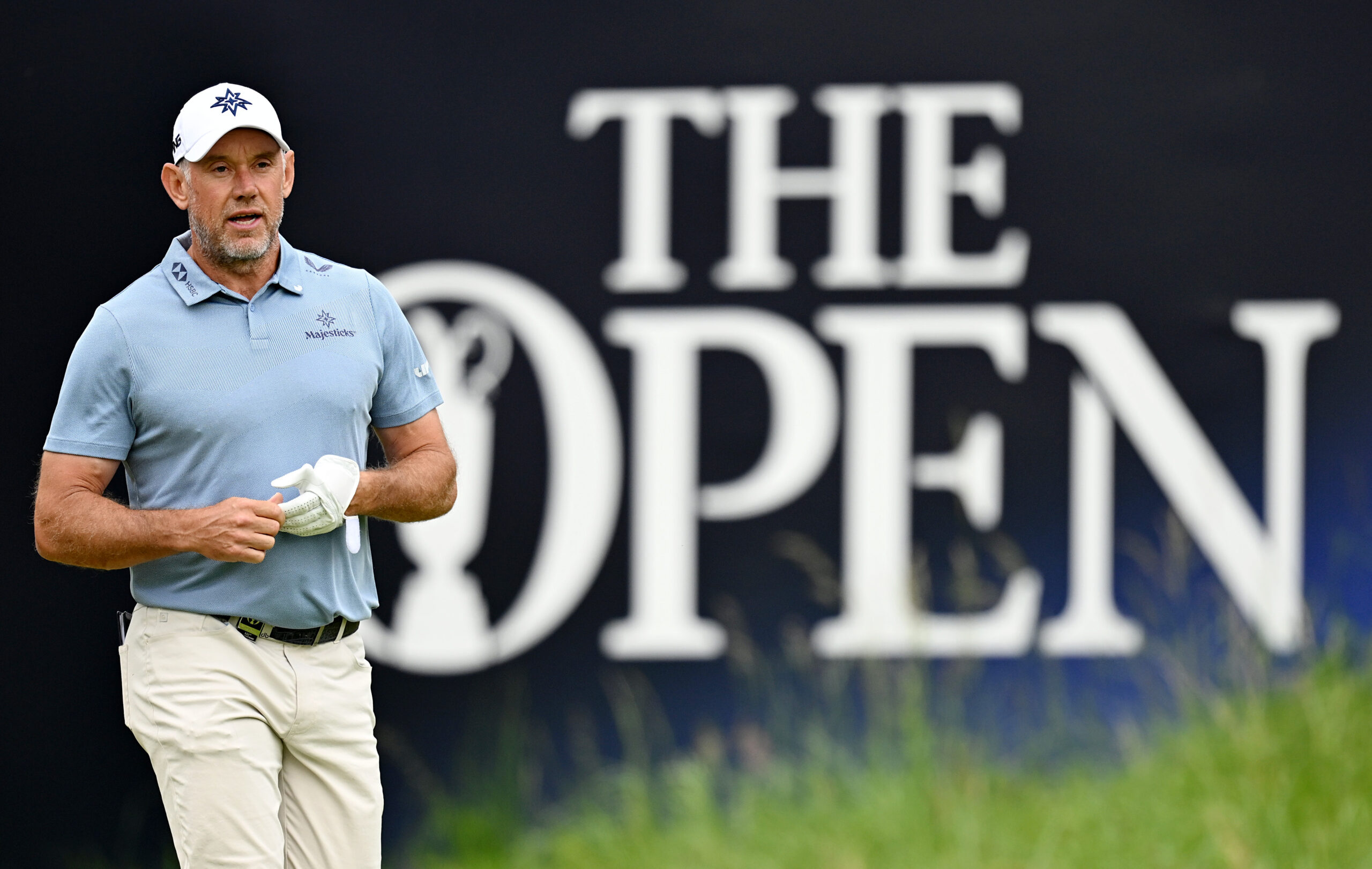Lee Westwood walks in front of an Open Championship banner