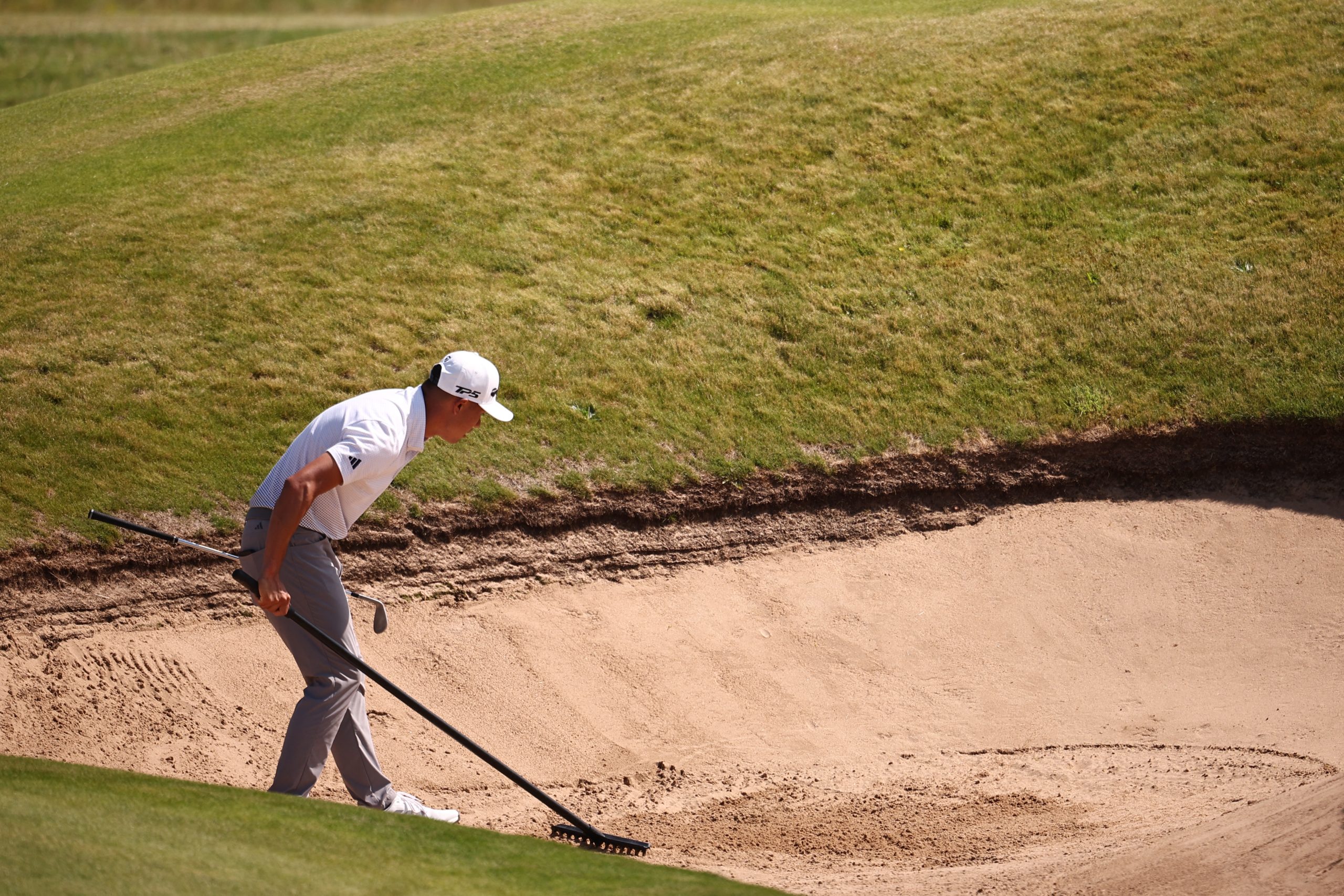 Collin Morikawa rakes a bunker