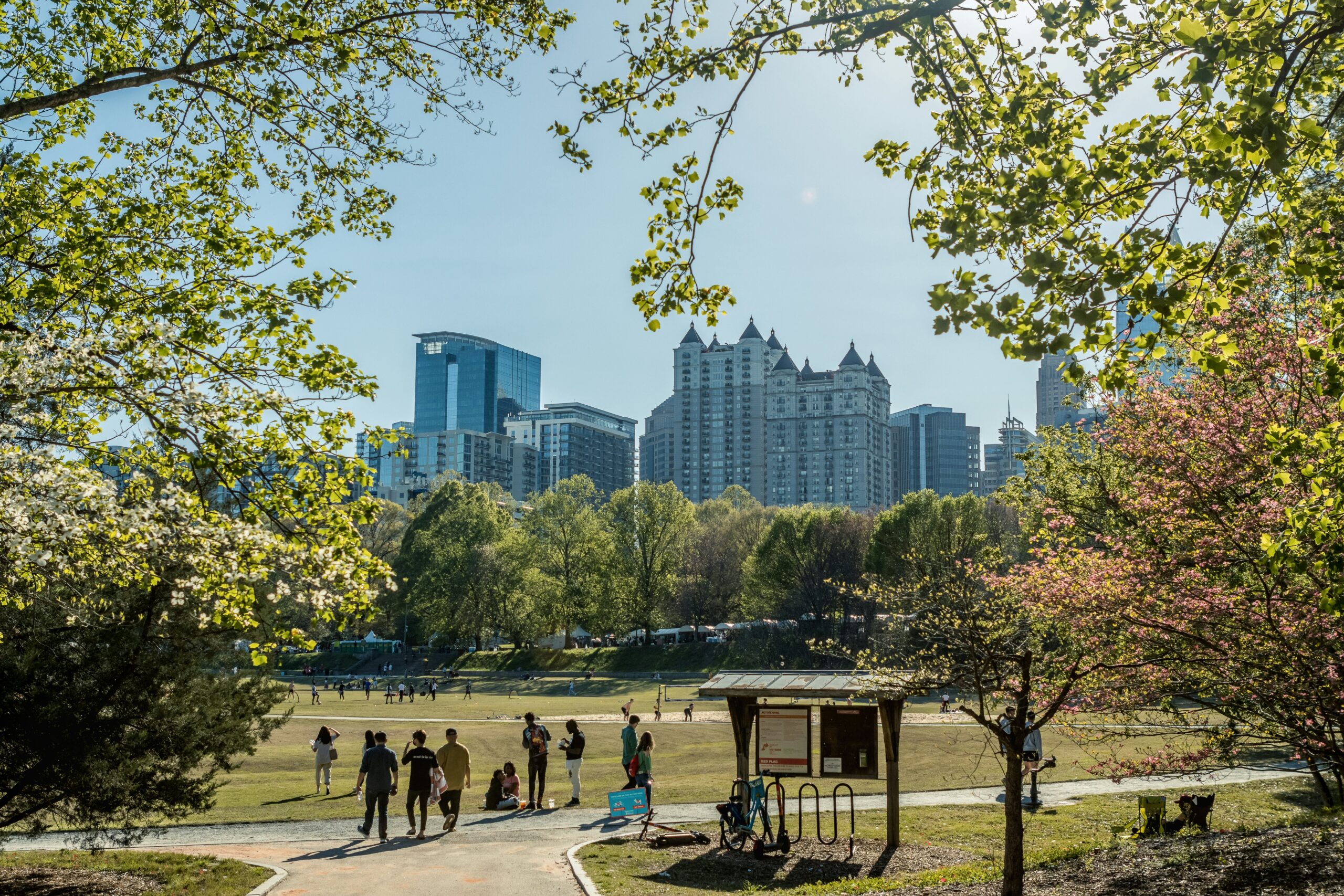 People strolling in Piedmont Park during the Dogwood Festival, with a view of the midtown Atlanta skyline in the background