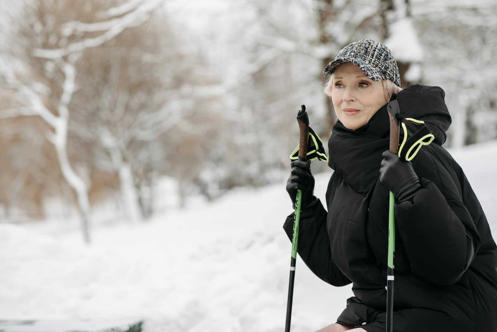 An older woman with trekking poles on a hike in winter (photo: Pavel Danilyuk, Pexels).